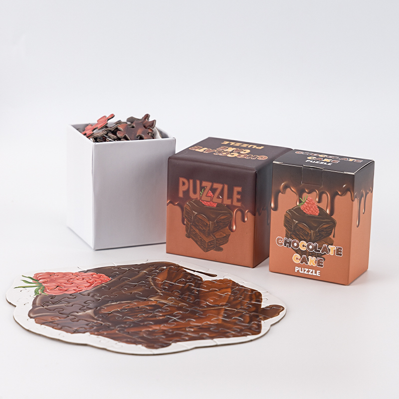 Chocolate-cake-shaped jigsaw puzzle displayed with printed packaging and loose pieces